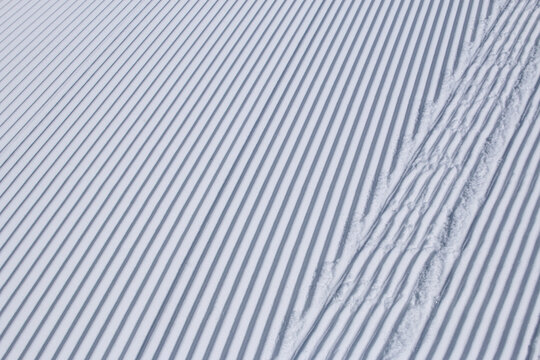 Straight lines in white snow on winter ski slope abstract texture background