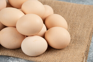 Pile of organic uncooked eggs with tablecloth on marble surface