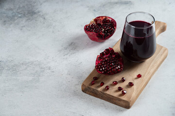 A glass cup of pomegranate juice on a wooden board