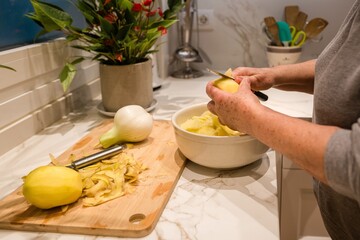 Hands cutting a potato to prepare a Spanish omelet