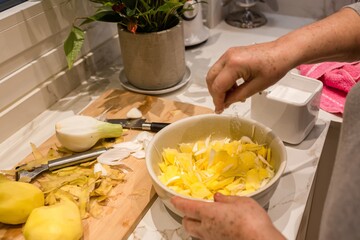 Woman's hands pouring salt on potatoes