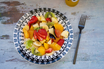 Natural and healthy fruit salad with orange set in a vintage plate, on a rustic surface. Healthy Food Concept, Healthy Life.