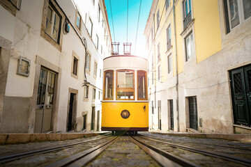 Trams in Lisbon city. Famous retro yellow funicular tram on narrow streets of Lisbon old town on a...