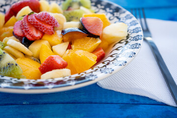 Natural and healthy fruit salad with orange set in a vintage plate on a rustic blue surface. Healthy Food Concept, Healthy Life.
