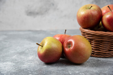 Wicker basket of red juicy apples on marble surface