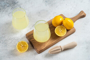 Two glass cups of lemonade and wooden reamer