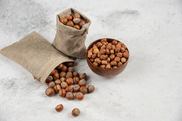 Pile of organic shelled and kernels of hazelnuts in burlap and in bowl