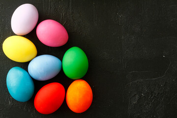 Top view a line of multicolored eggs on a black isolated background.  Dyed Easter eggs. Copy space for your text. Flat lay style. Top view.