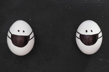 Easter eggs with Corona virus COVID19 protection concepts. DIY Do It Yourself easter eggs wearing mask for Easter holidays decoration on black background Selective focus with copy space. 