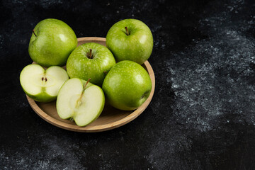 Fototapeta na wymiar Whole and sliced ripe green apples on wooden plate