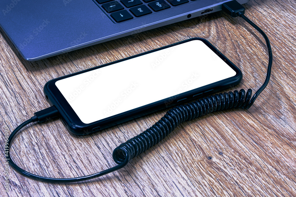 Poster mock-up of a smartphone with a white screen close-up being charged from a laptop on the background o