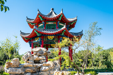 closeup shot of china style architecture pavilion with upturned eaves gray roof and painting in the  garden and stone sculpture nice place for family rest, own garden design, tourism, meditation