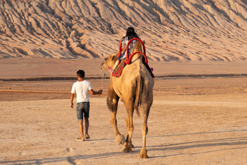 Girl ride on camel in desert near the flame mountain