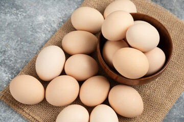 Wooden bowl of organic raw eggs on marble surface