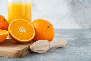 Glass pitcher of juice with sliced orange fruit on a wooden board