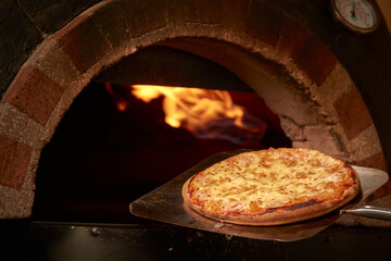 pizza saliendo del horno con llamas