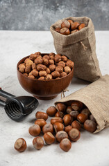 Bowl of organic hazelnut kernels and shelled hazelnuts on marble background