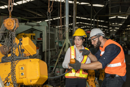 Female mechanic engineer or worker with hardhat and safety gears is working with her supervisor in a factory checking the function of a system