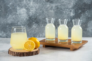 A glass cup of fresh lemon juice on a wooden board