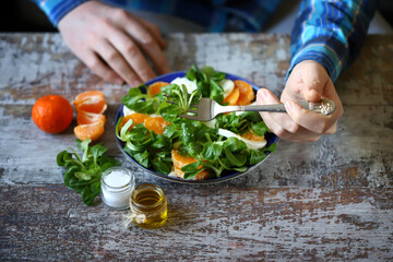 Man eating healthy salad with tangerine, mozzarella and mash salad.