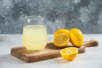 A glass cup of fresh lemon juice on a wooden board