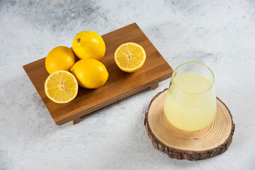 A glass cup of fresh lemon juice on a wooden board