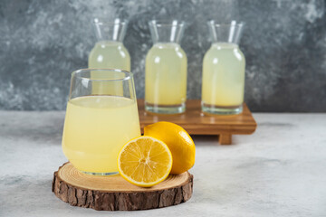 A glass cup of fresh lemon juice on a wooden board