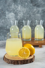 A glass cup of fresh lemon juice on a wooden board