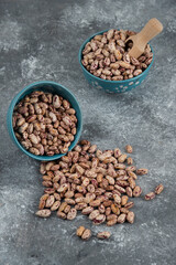 Raw bean grains displayed in bowls on marble surface