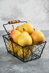 Pile of fresh yellow pears in metal bucket on marble surface