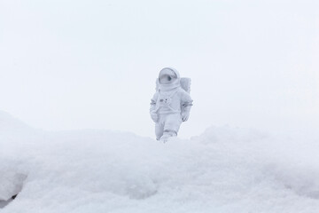 Statuette of an astronaut confidently explores alien planet's surface. Cold planet covered with snow.