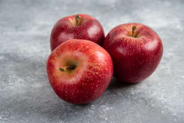 Three ripe red apples placed on marble surface