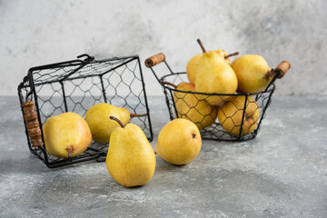 Bunch of fresh yellow pears in metal bucket on marble surface
