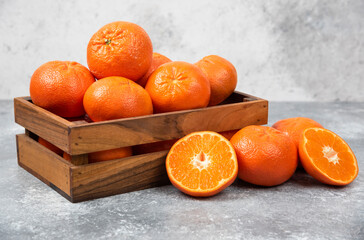 A wooden old box full of juicy orange fruit on stone background