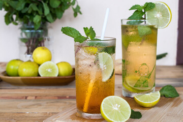 Fototapeta premium herbal healthy drinks cold lemon tea for health care with peppermint leaf and lemon slice arrangement flat lay style on background wooden