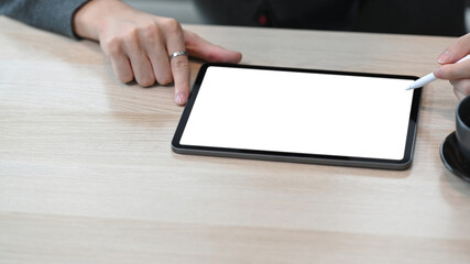 Close up view of man holding stylus pen pointing on digital tablet.