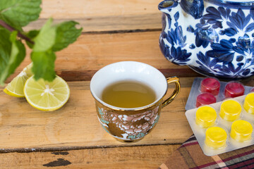 herbal mix honey lemon hot healthy drinks with lozenge sore throat pills and peppermint leaf ,lemon slice arrangement flat lay style on background wooden