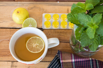herbal mix honey lemon hot healthy drinks with lozenge sore throat pills and peppermint leaf ,lemon slice arrangement flat lay style on background wooden