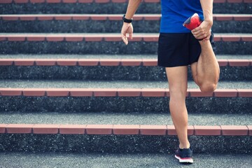 Sporty man stretching exercise for warming up before running onthe stairs in park or gym workout. Fitness and healthy lifestyle concept.