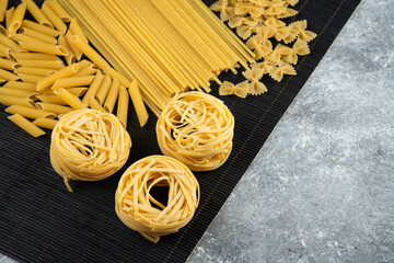 Various uncooked pasta on black bamboo sheet