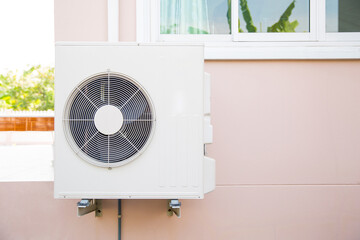 External split wall type of house air conditioner compressor unit installed on the outside of the building.