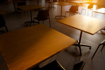 Tables and chairs that is arranged spaced or social distancing in the dining room without people.