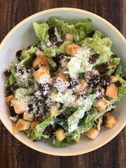 closeup of healthy Italian Caesar salad with vegetables and croutons on a dark wood table