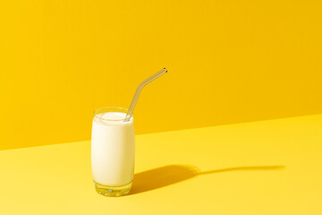 Glass of milk minimalist on yellow background. Single glass of milk