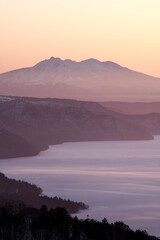 早朝の高所から見る遠くの山の稜線と眼下の湖。日本の北海道の観光地の美幌峠からの屈斜路湖と斜里岳の眺め。