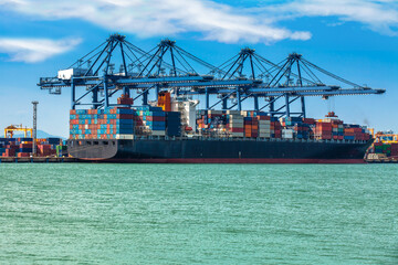 Container Cargo freight ship with working crane loading bridge in shipyard at dusk for Logistic Import Export background
