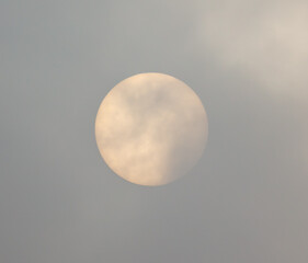 The sun shines behind the clouds during