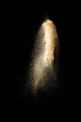 Launch brown particles exploding on black background. Brown dust splashing.