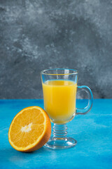 A glass cup of juice with slice of orange