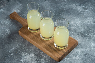 Three glass jugs of fresh lemonade on a wooden board